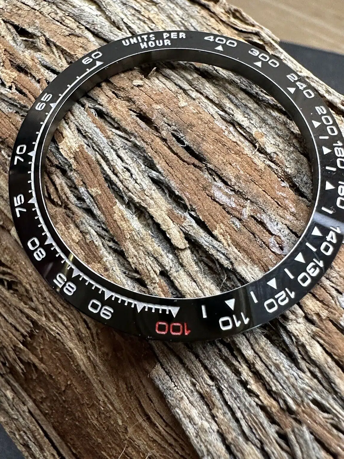 Close-up of a black ceramic watch bezel with detailed markings illustrating design and material quality