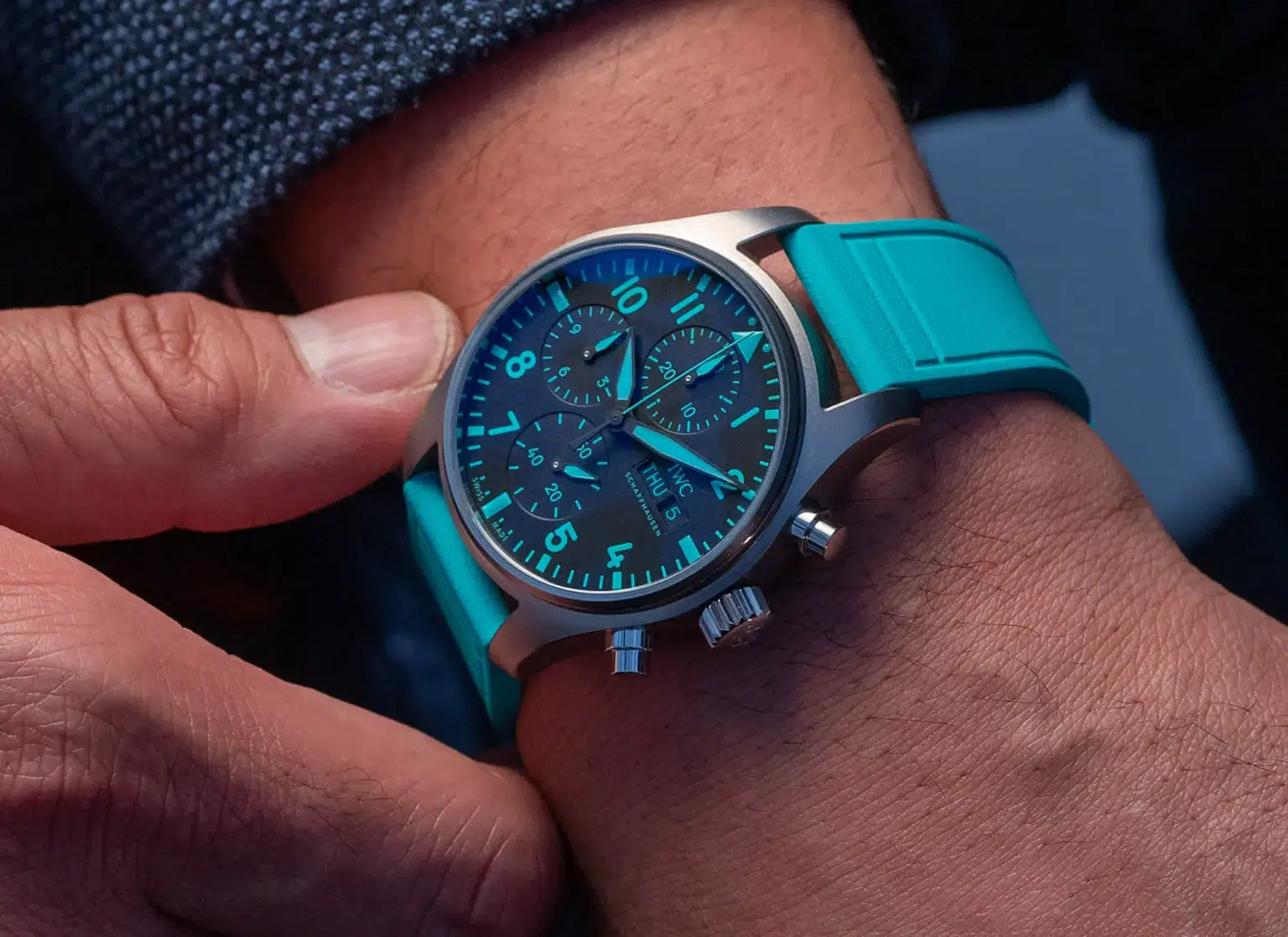 Close-up of an IWC pilot watch featuring luminous numerals, chronograph subdials, and a vibrant turquoise strap